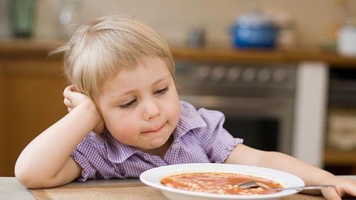 Un enfant devant son assiette.