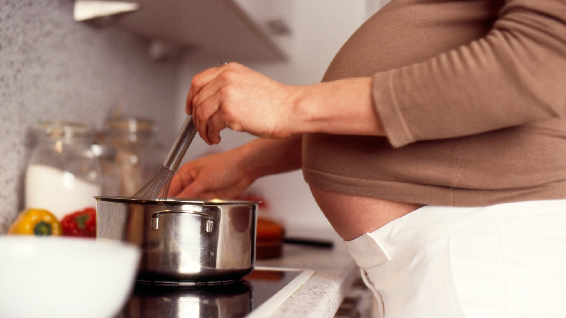 Une femme enceinte cuisine.