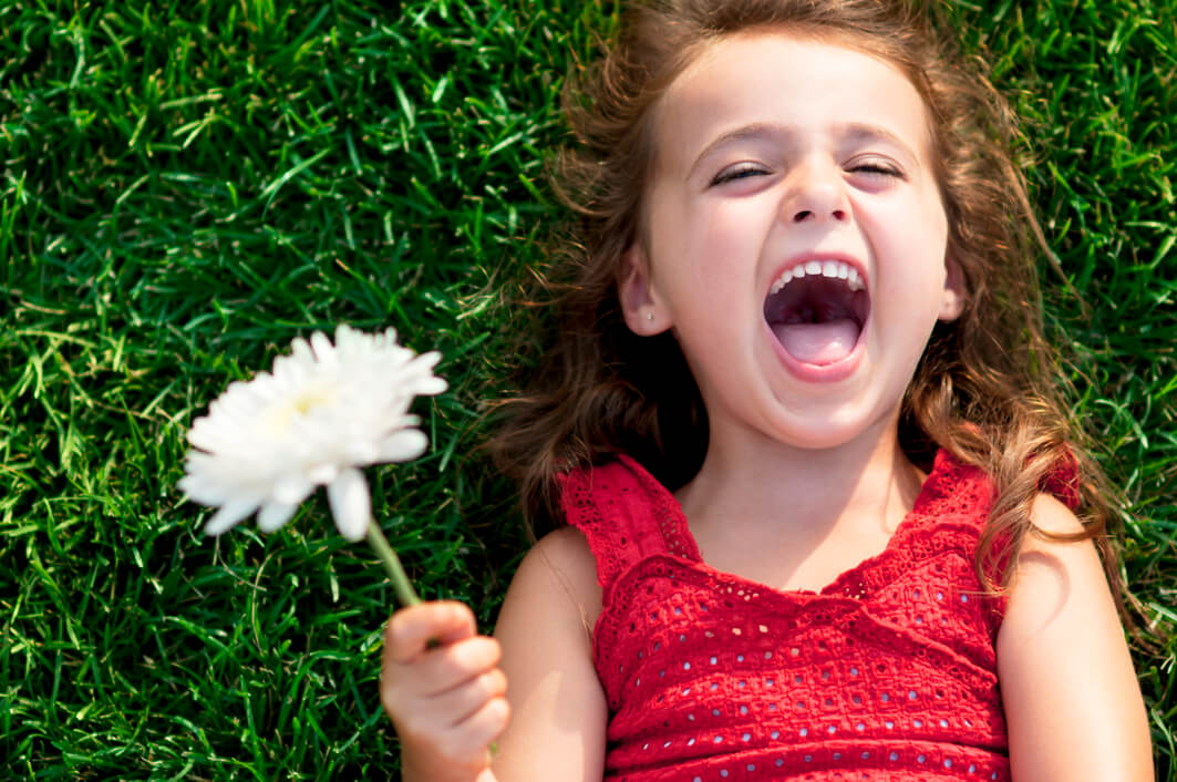 Une jeune fille allongée dans l'herbe avec une fleur dans la main. 