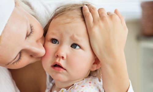 A mother kissing her baby girl's cheek.