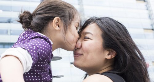 Une jeune fille embrassant sa maman sur le nez.