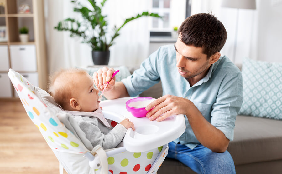 A father spoon-feeding his baby.