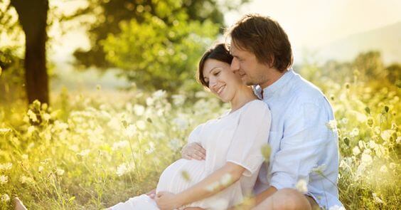 Une femme enceinte avec son partenaire dans la nature.