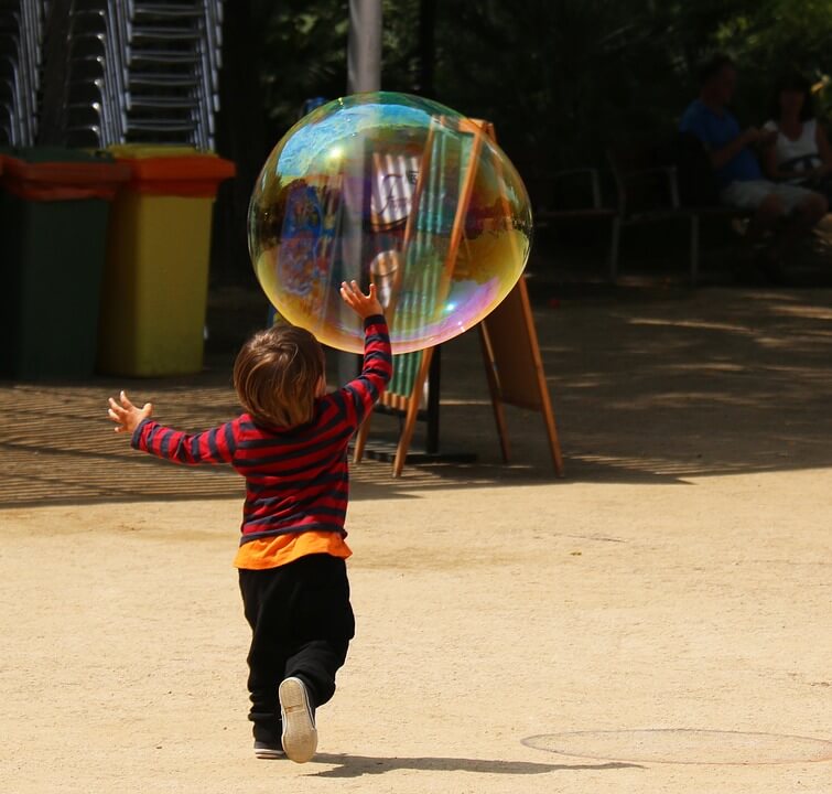 Criança brincando com bolha de sabão gigante.