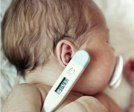 Un bébé malade avec un thermomètre.
