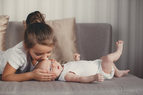 Hermana mayor dándole muchos besos a su hermano bebé.