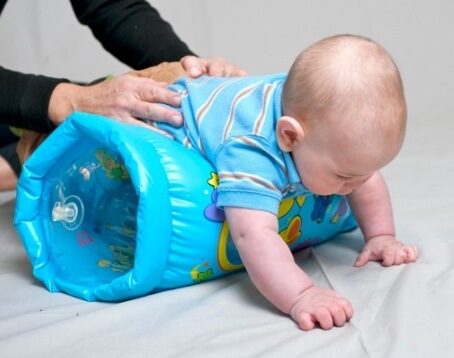 Un bébé qui roule sur un rouleau gonflable. 