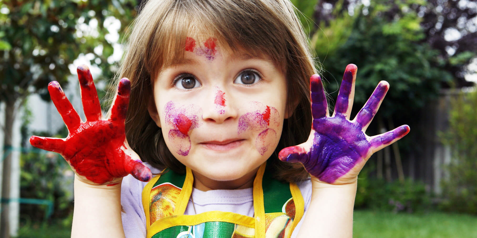 Une jeune fille avec de la peinture sur les mains et le visage.