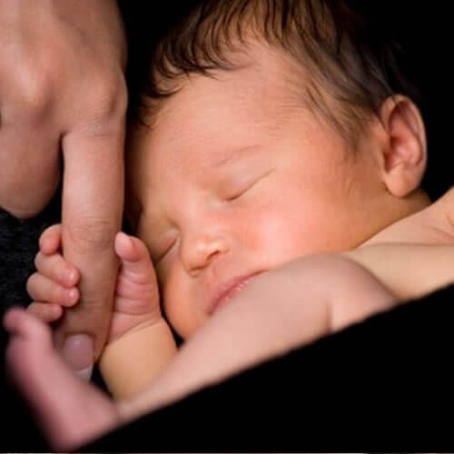 Un nouveau-né qui agrippe le doigt d'un adulte. 