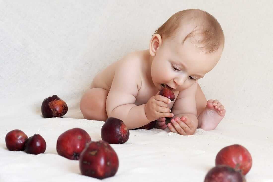 Un enfant qui joue avec des cerises.