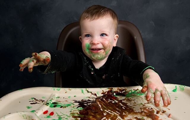 A baby that's playing with his food.