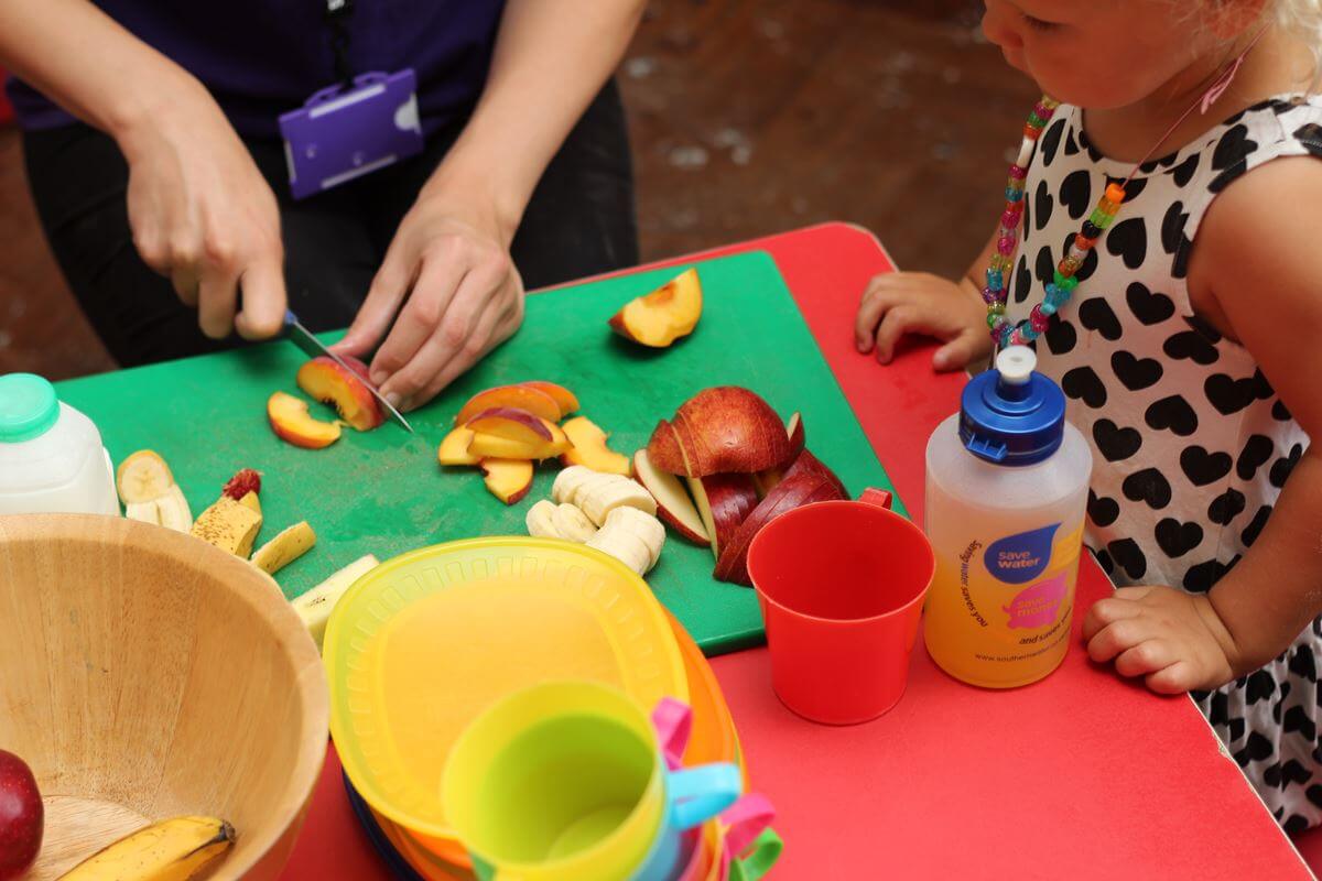 Adulte préparant un goûter sain de fruits pour une petite fille