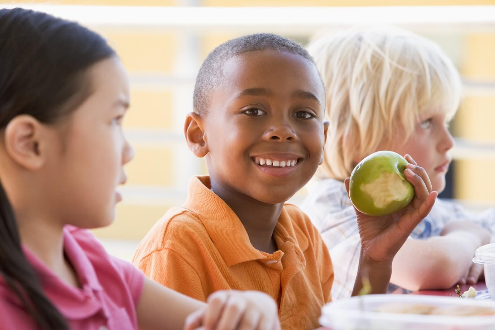 Un enfant avec une pomme croquée, une idée pour des goûters sains