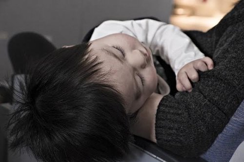 Un jeune enfant allongé dans les bras de sa maman. 