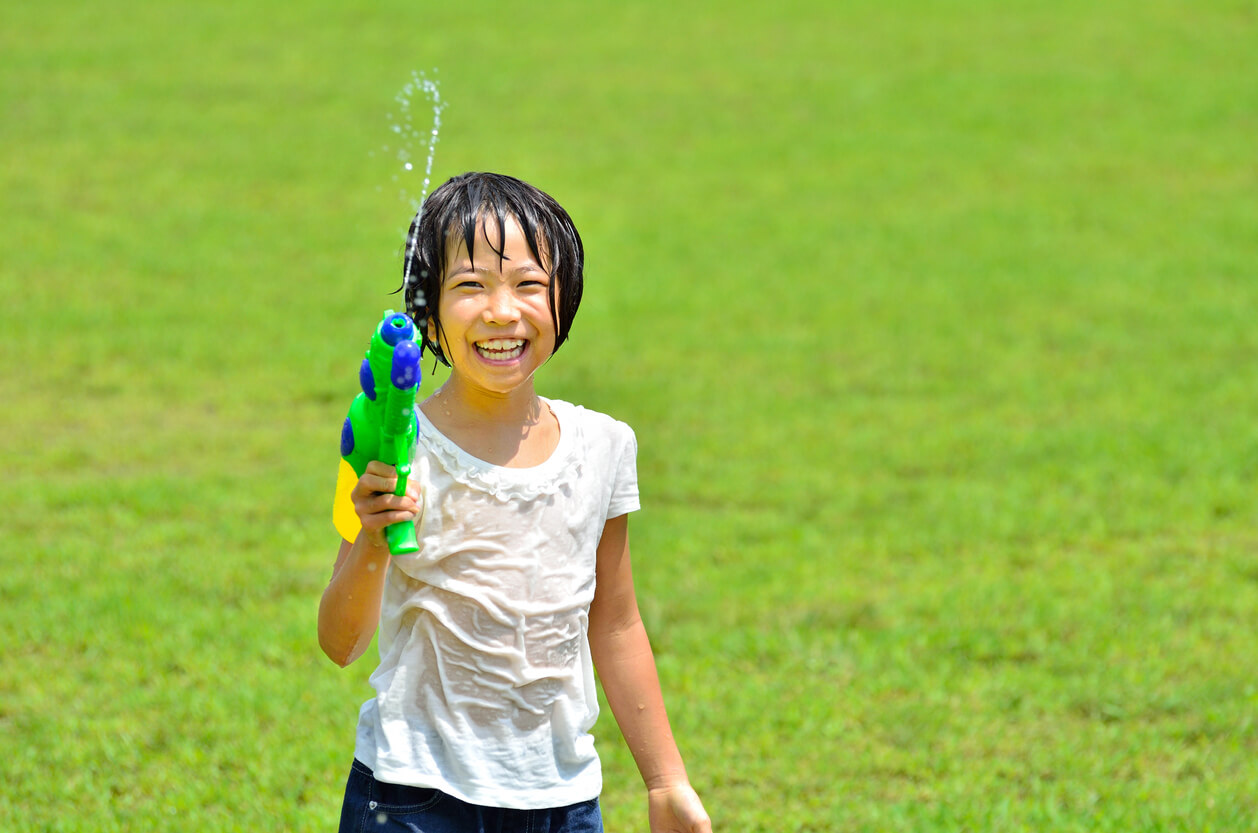 nina nena mojada agua pistola diversion juego feliz felicidad pasto aire libre verano prevencion insolacion golpe de calor refresca