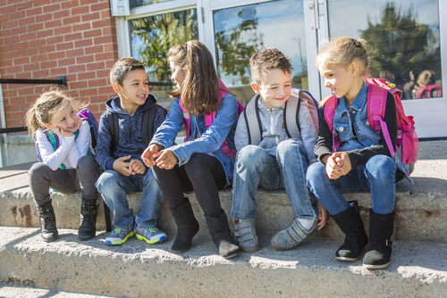 Un grupo de niños pequeños hablando en el patio a la salida del colegio