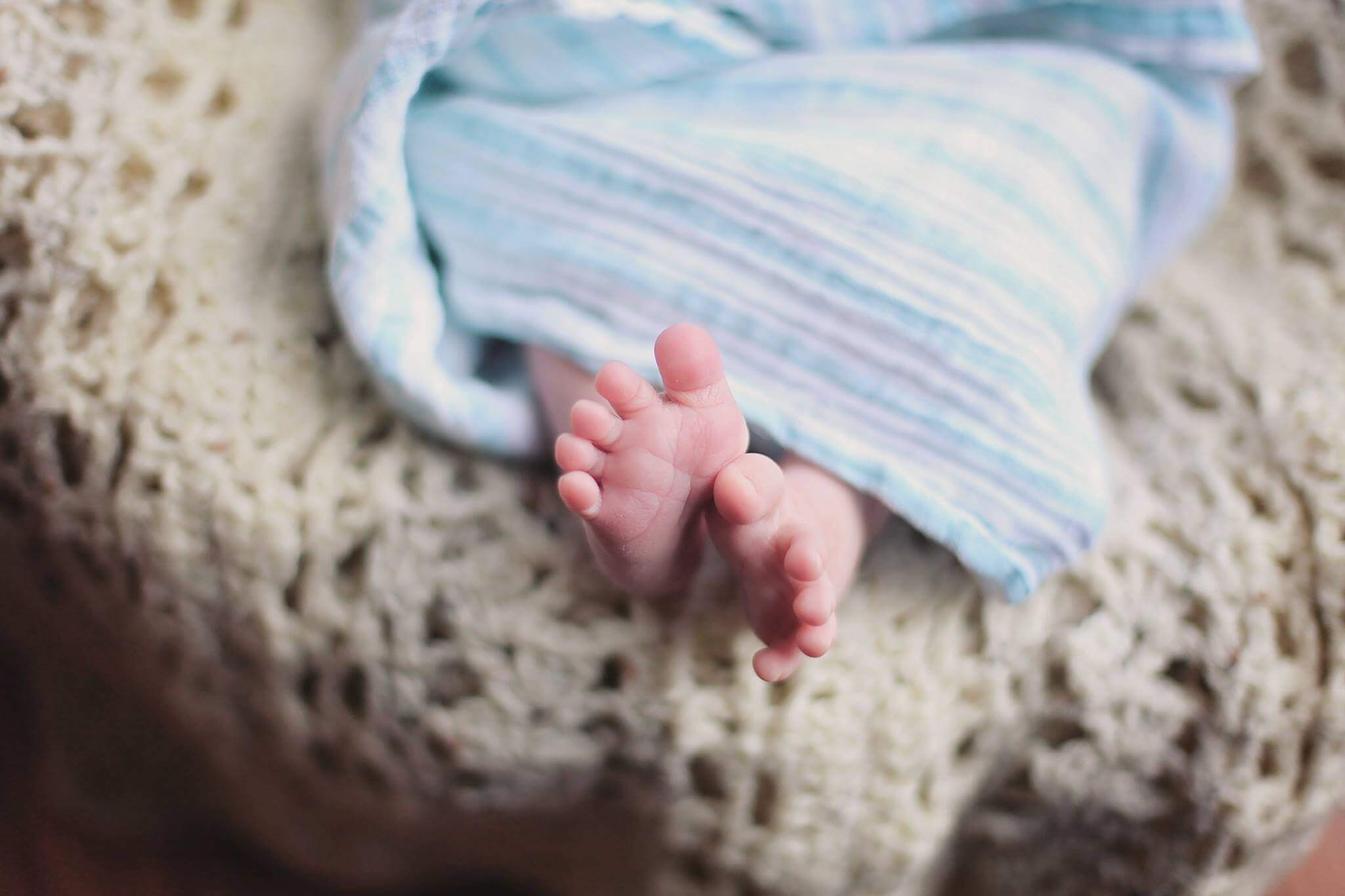 Pies de bebe bajo una manta azul