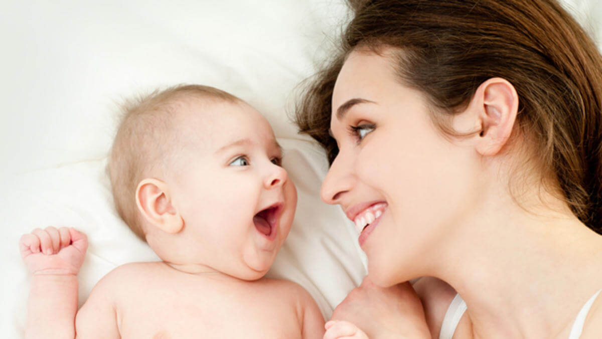 Madre en la cama con su bebe sonriendo