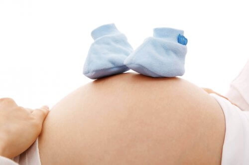 Deux chaussons de bébé sur le ventre d'une femme enceinte. 