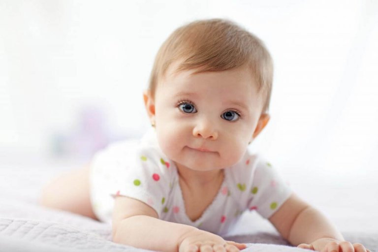 Bebé alegre sorprendido yace boca abajo sobre una alfombra de