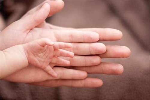 Las manos de mamá y la manita de la bebé