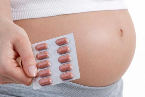 Mujer embarazada sujetando pastillas de acido folico