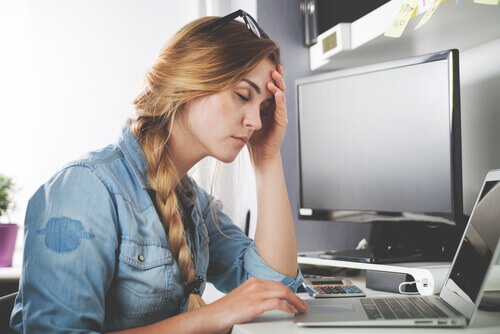 Une femme souffrant d'un mal de tête devant l'ordinateur.