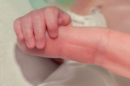 Bebé recién nacido agarrando el dedo de su madre.