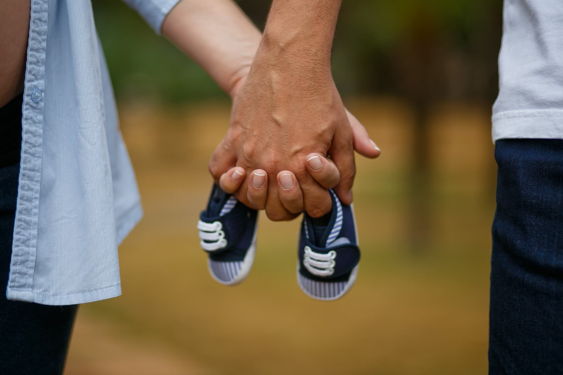 Padre y madre con las manos entrelazadas y unos zapatos de bebé