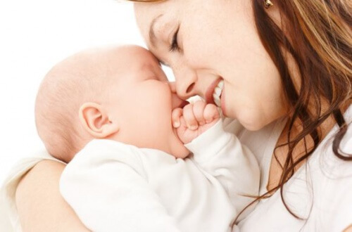 Madre abrazando a su bebe con los ojos cerrados