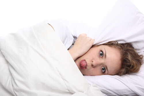 Mujer en la cama tapada debido al dolor de cabeza durante el embarazo