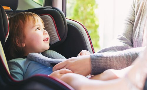 Padre atando a su hijo el cinturón de la silla del coche para poder viajar seguro.