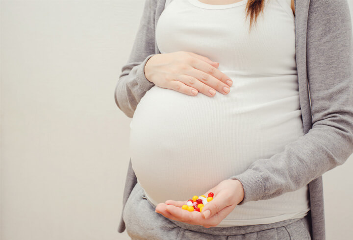 Mujer embarazada mostrando unas pastillas