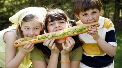 Tres hermanos compartiendo un bocadillo para evitar el síndrome del hermano mediano.