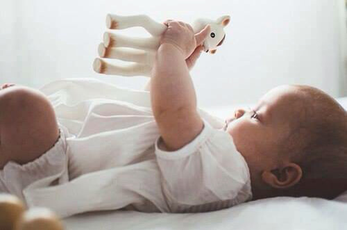 Un bebé sujetando un juguete blando.