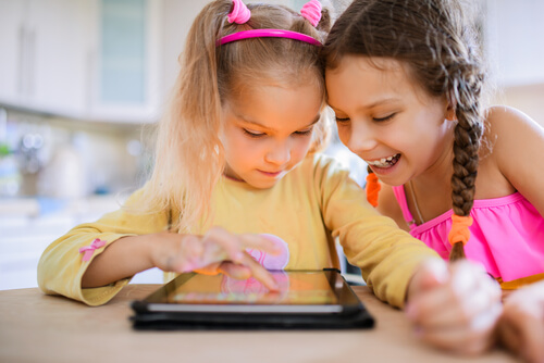 Dos niñas jugando en línea con una tablet.