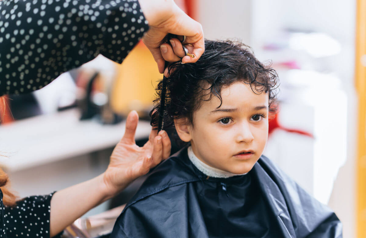 Niño con cabello crespo recibiendo un corte.