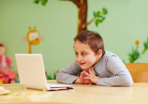 Niño con discapacidad intelectual mirando un ordenador.