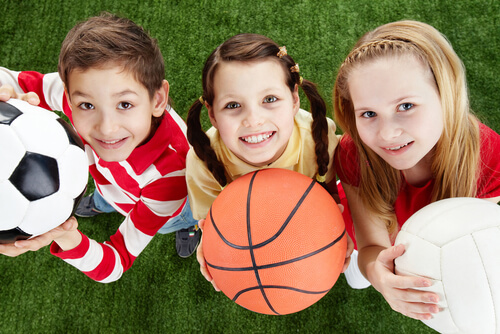 Trois enfants avec trois ballons de sports différents.