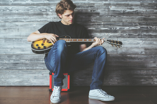 Un adolescent qui fait de la guitare.