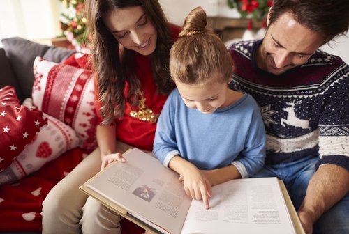 Padre leyendo con su hija algunos cuentos sobre la Navidad para niños.