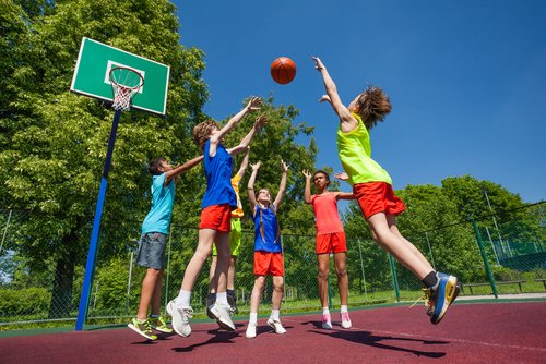 Niños jugando al baloncesto teniendo cuidado de no hacerse lesiones deportivas.