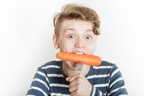 Un enfant qui mange une carotte.
