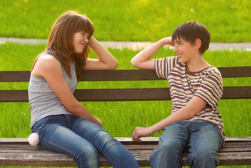 Adolescentes enamorados sentados en un banco del parque.