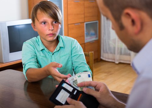 Niño recibiendo una paga semanal como parte de las actividades de educación financiera.