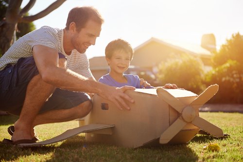 Padre e hijo con el avión de juguete hecho de cartón.