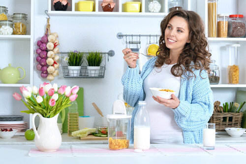 A pregnant woman eating a bowl of cereal and milk.