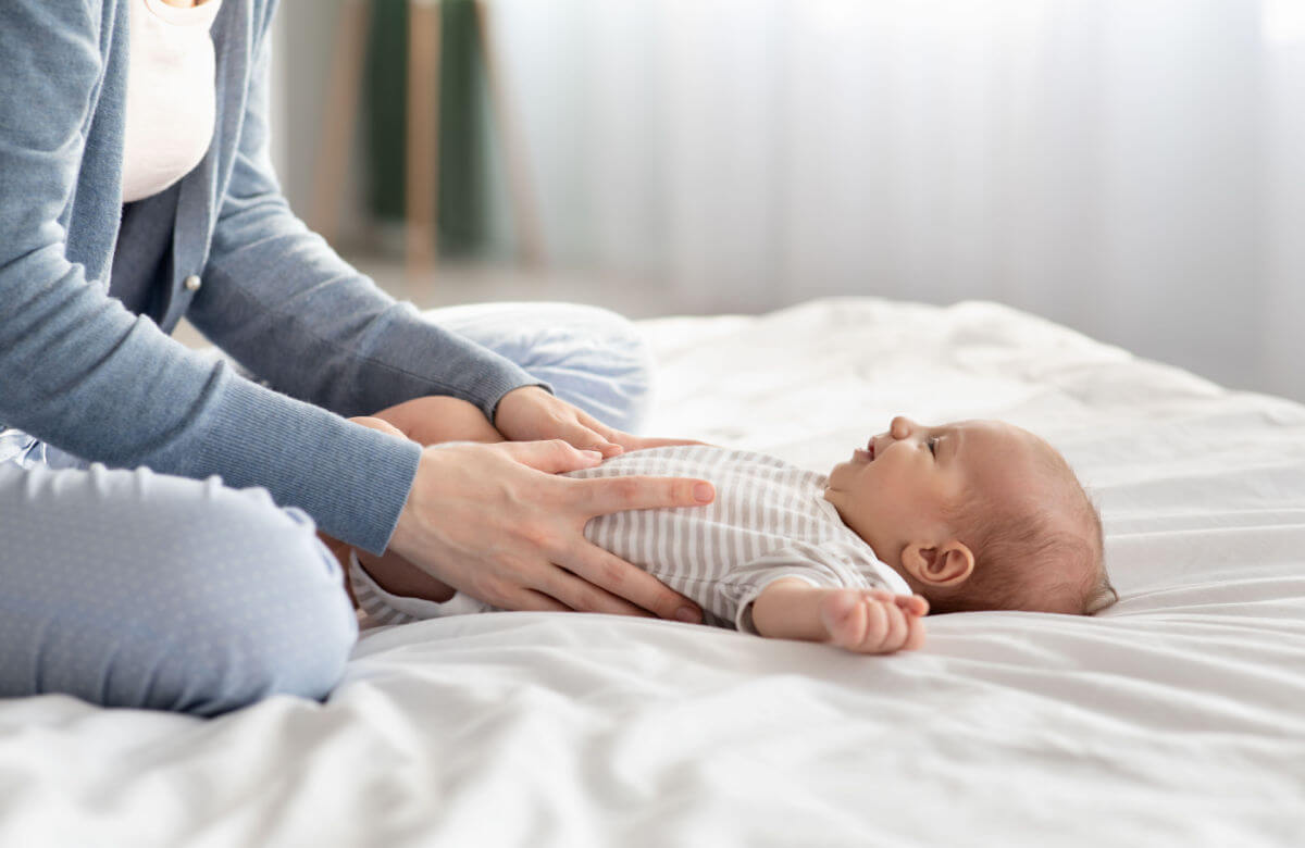 Mamá deslizando los pulgares hacia los lados del abdomen de su bebé.