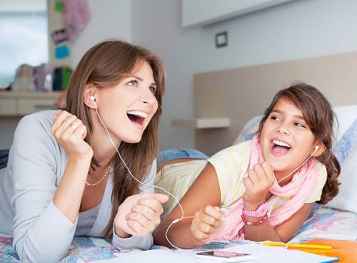 Madre escuchando música con su hija en la cama.