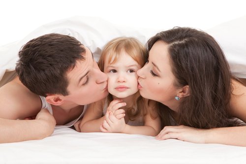 Padres dándole muchos besos a su hija.